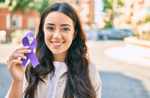 A woman holding a purple ribbon