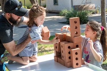 Two children playing with bricks and stacking them