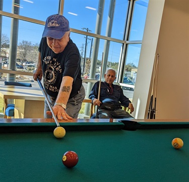 An older man enjoying a game of pool