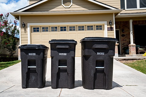 Three brown trash cans of differing sizes.