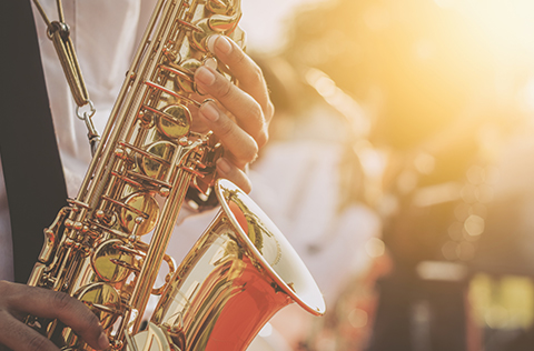 Closeup of a saxophone player's hands holding a saxophone.
