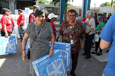Older adults carrying donated box fans at a Project Cool distribution event.