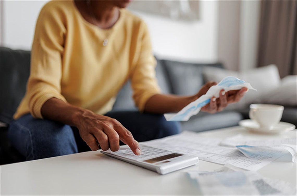 A woman using a calculator to add expenses