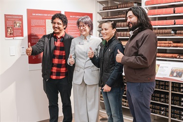 City Clerk, Mayor, and two City Councilmembers from San Antonio posing in front of a museum exhibit during the Grand Opening.