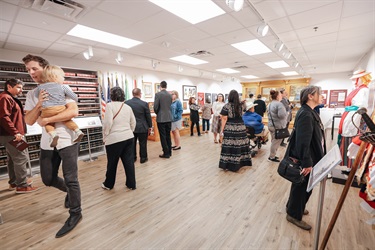 A group of individuals gathered inside the Municipal Archives Museum following the Grand Opening ceremony, viewing exhibits and socializing.