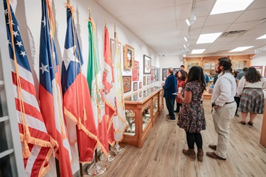 A group of individuals gathered inside the Municipal Archives Museum following the Grand Opening ceremony, viewing exhibits and socializing.