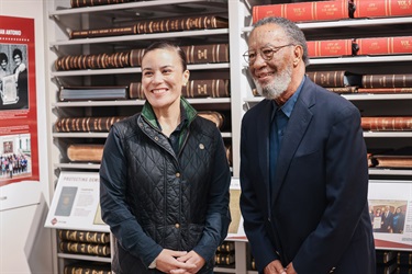 City of San Antonio Mayor standing with another individual in front of a museum exhibit, posing for a photo during the Grand Opening.