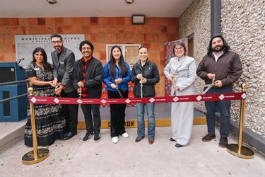 Seven individuals standing in a row behind a ribbon, each holding scissors and preparing to cut the ribbon at the Grand Opening ceremony.