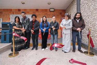 Seven individuals standing in a row, cutting the ribbon together during the Grand Opening ceremony of the Municipal Archives Museum.