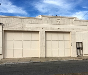 (After): A one-story commercial building with two large garage doors, a smaller door and freshly painted light tan exterior walls.