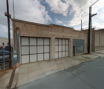 (Before): A one-story commercial building with two large garage doors, a smaller door and worn tan exterior walls.