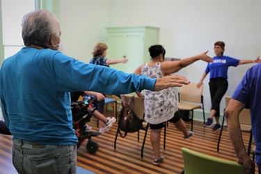 A group of seniors energetically working out in a room, showcasing their enthusiasm and joy through their synchronized movements.