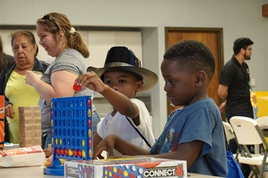 Two children engrossed in a game, sitting at a table, focused and enjoying their playtime together.