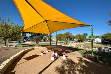 Benches shaped liked mushrooms under a yellow awning.