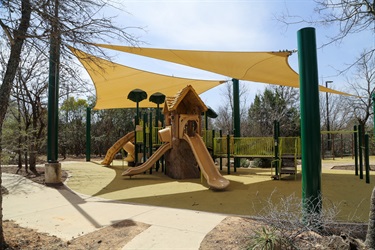 A playground featuring a colorful slide beside a large tree.
