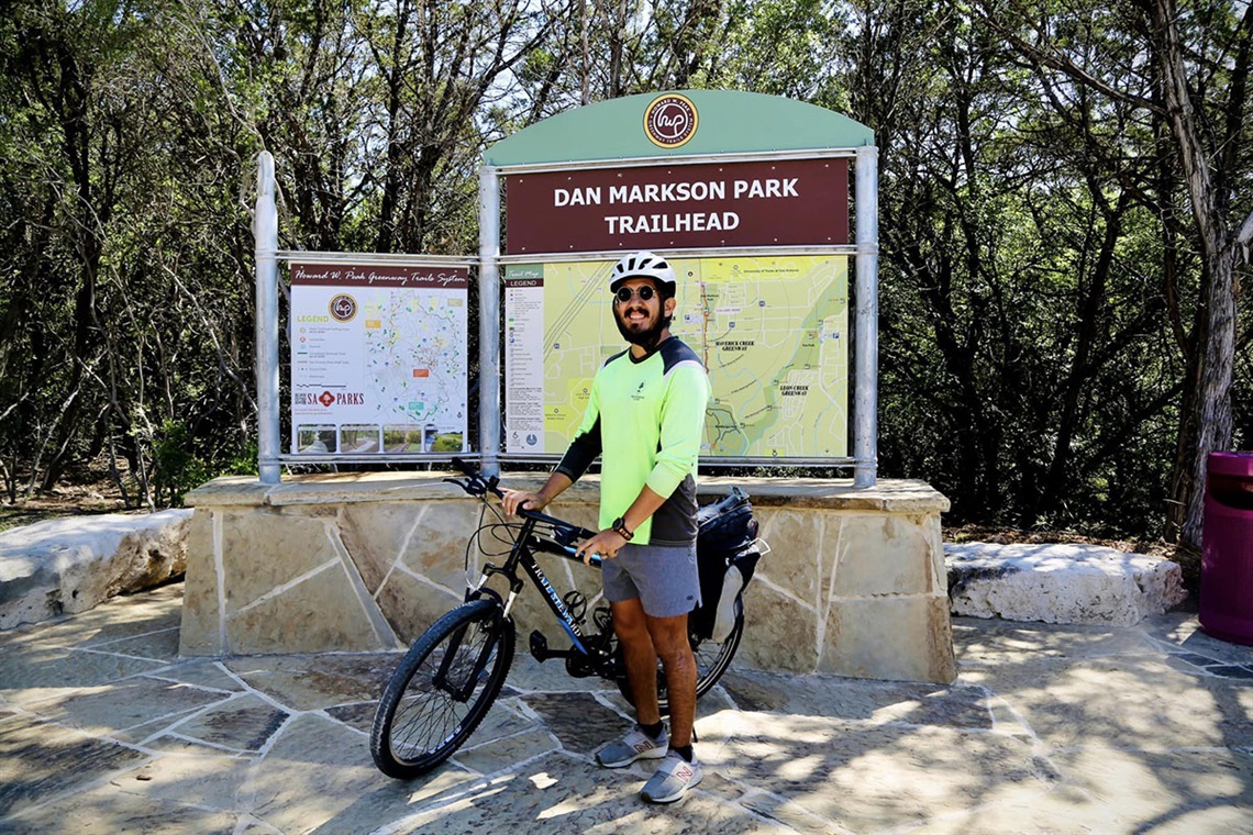 Dan Markson Park trailhead sign with biker in front