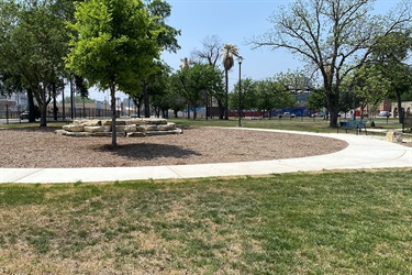 Paved walkway encircled with wooden chips and stone seats