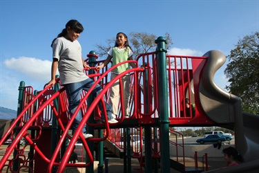 A vibrant red slide with two kids having fun.