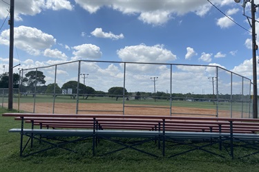 A view of the second baseball field, showcasing a fence and benches for players and spectators.