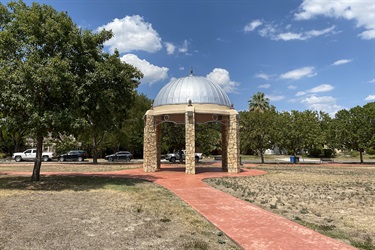 A serene park setting featuring a gazebo, complemented by a red brick walkway.