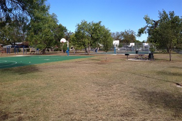 A view of two basketball courts surrounded by picnic benches and a playground.