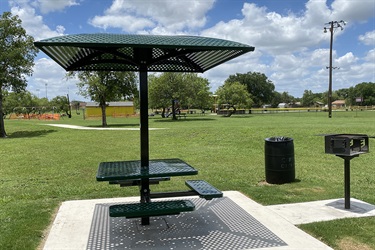 A park's covered picnic area featuring a table and umbrella.