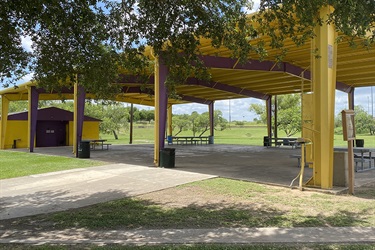 A vibrant yellow pavilion with picnic tables.