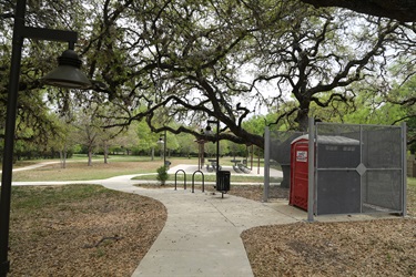 A path leading to a red portable toilet and then to the covered picnic area.