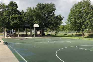 Basketball court with picnic benches and trees in background.