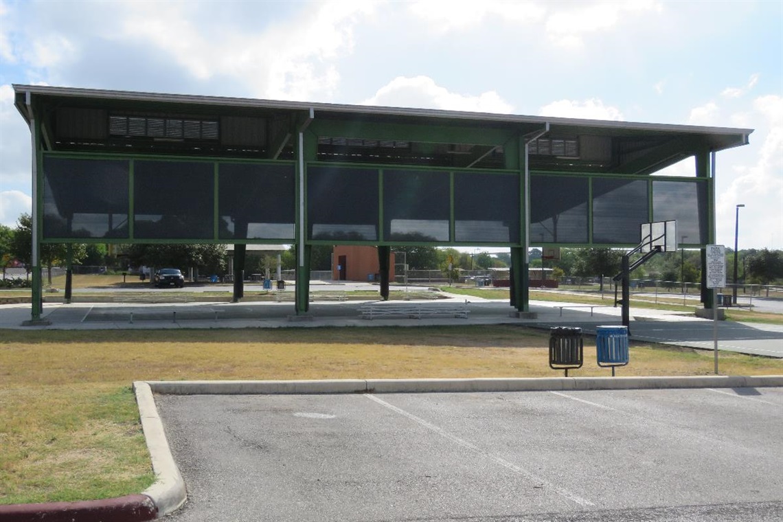 A covered basketball court surrounded by a parking lot.