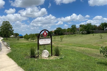 Park sign in grassy field.