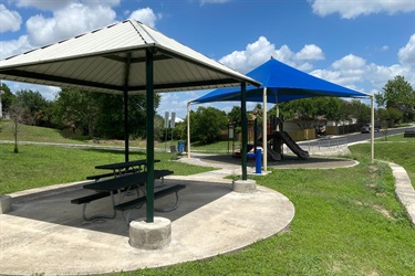A serene park with a picnic table and gazebo, ideal for picnics and events.