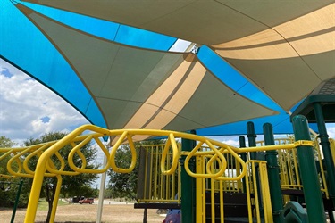 A playground with a big shade structure providing shelter from the sun.