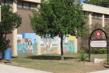 Colorful mural on wall with green leafy tree nearby.
