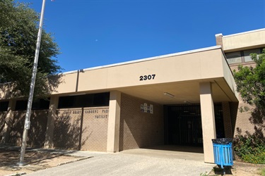 Front entrance to school building with steps, glass doors, and a sign displaying the facility's name.