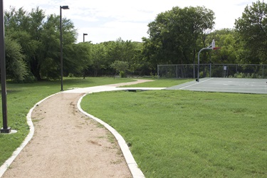 Dirt trail with basketball court to its right