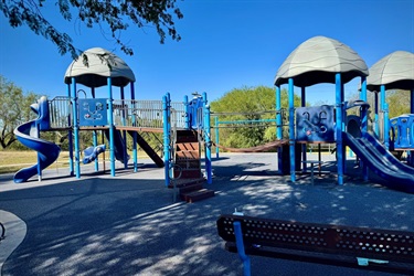 Blue playground with slides, climbing structures, and benches.