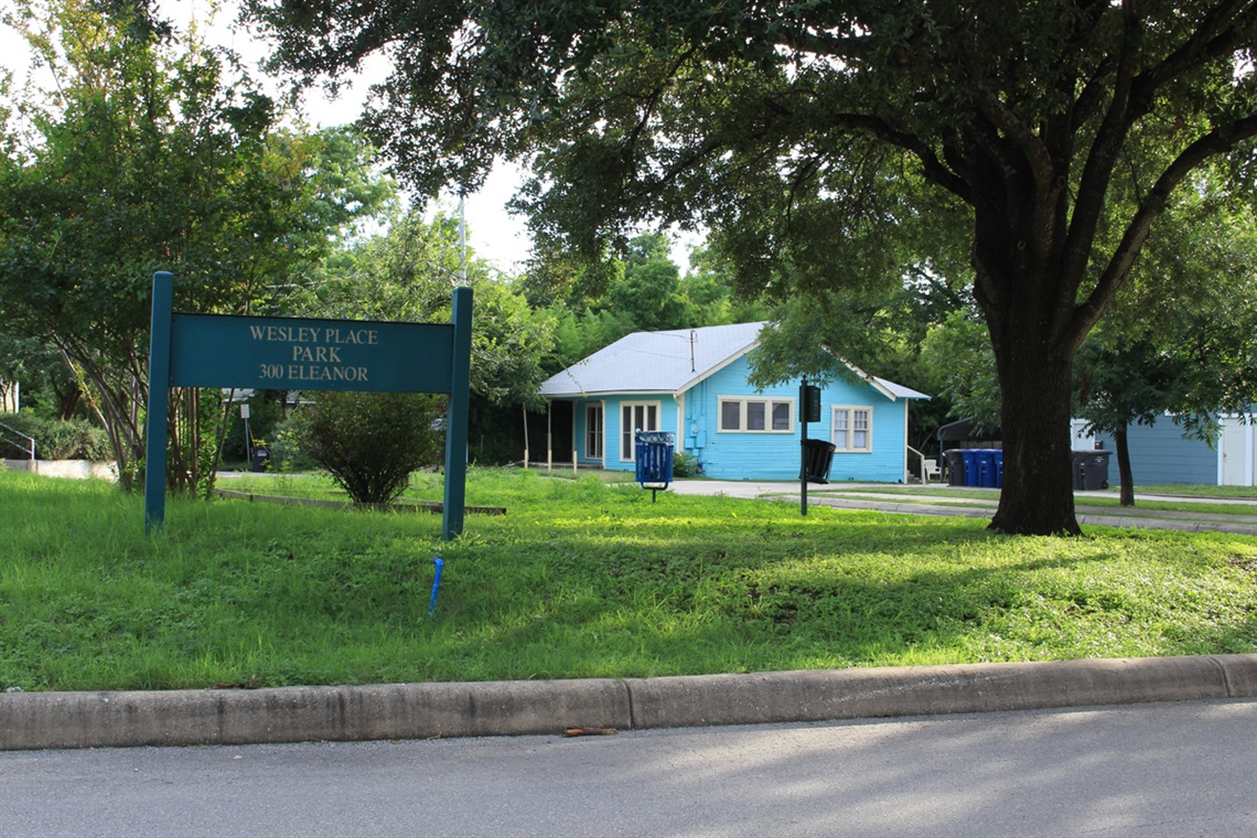 Blue Wesley Place sign with a blue house in the background