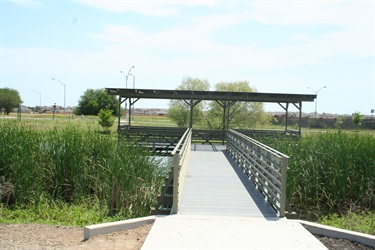 A wooden bridge spanning a peaceful pond, surrounded by lush greenery