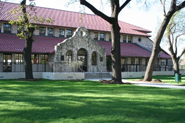 A building featuring a vibrant red roof in front of trees