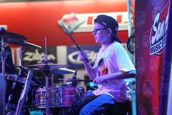 Young boy playing drums with a big smile on his face.