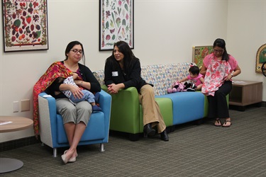 Two mothers, one talking with a SAMHD employee, while breastfeeding their covered children