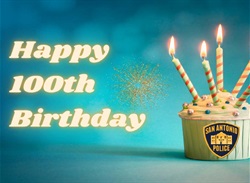 Happy 100th Birthday text to the left of cupcake with five lit candles.