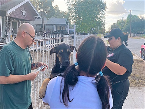 ACS worker speaking with citizens holding a dog at there residence.