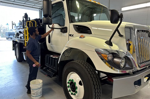 City employee inspecting a heavy-duty truck inside a fleet maintenance shop