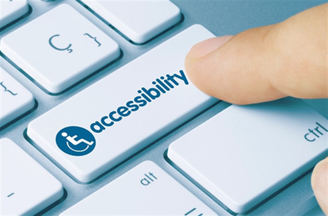 Finger pressing keyboard key labeled “Accessibility” with wheelchair icon