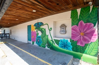 Mural of vibrant flowers and butterflies on the side of Gibson Tavern, enhancing the building's exterior with colorful art.