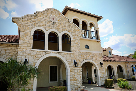 The Ravello photo for the apartment complex shows the Spanish style main office building with a view of the pool including ADA ramps and lounge chairs.