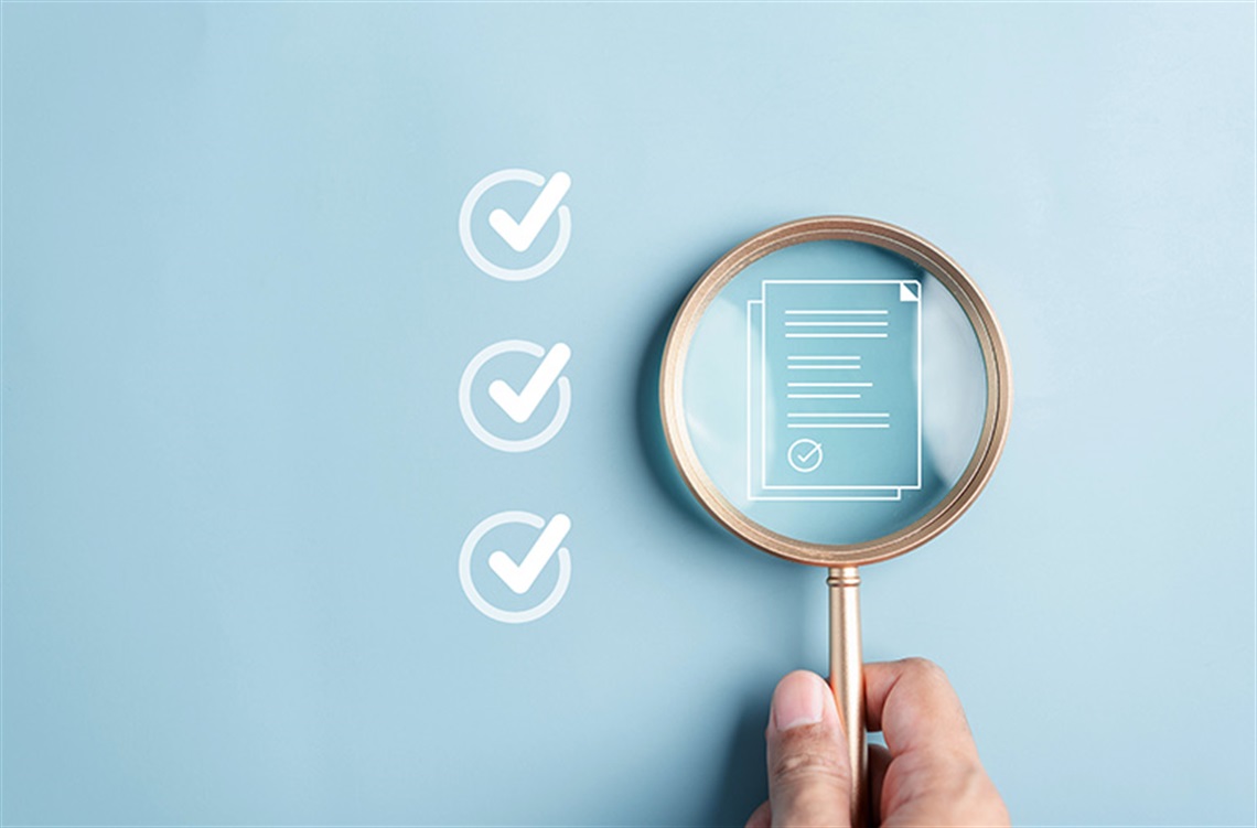 Magnifying glass reviewing report on a wall