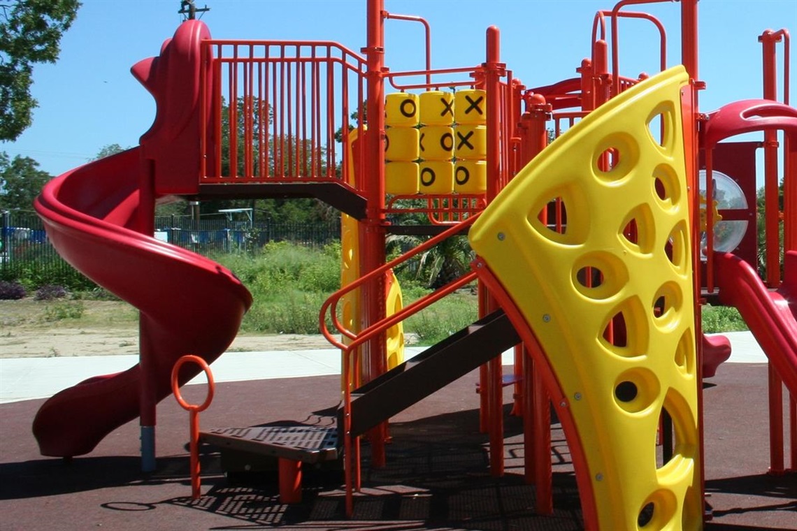 A colorful playground featuring a regular slide and a creatively designed slide that looks like a pizza slice.